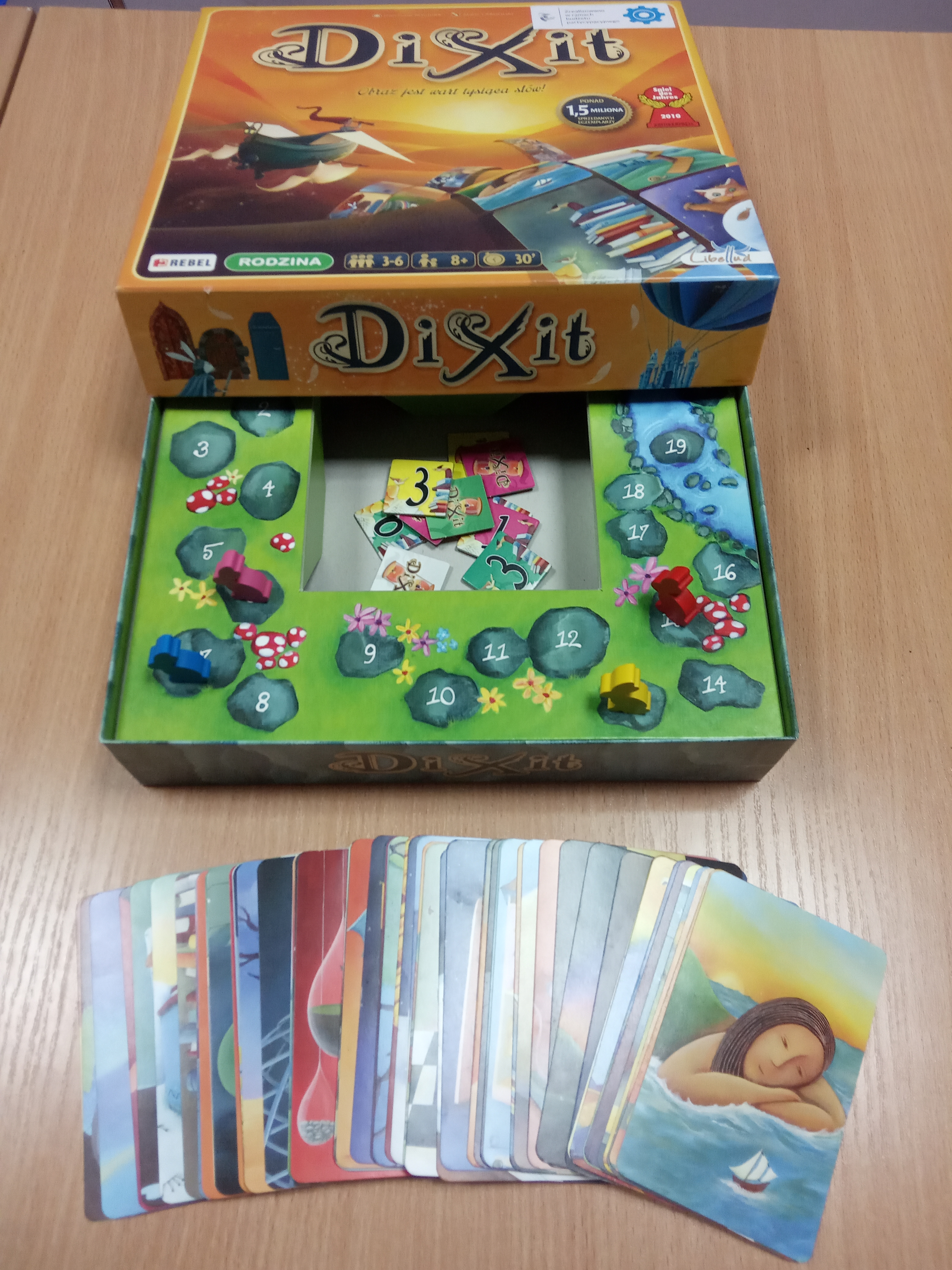 Otwarte opakowanie gry o nazwie Dixit, karty do gry są przed opakowaniem.