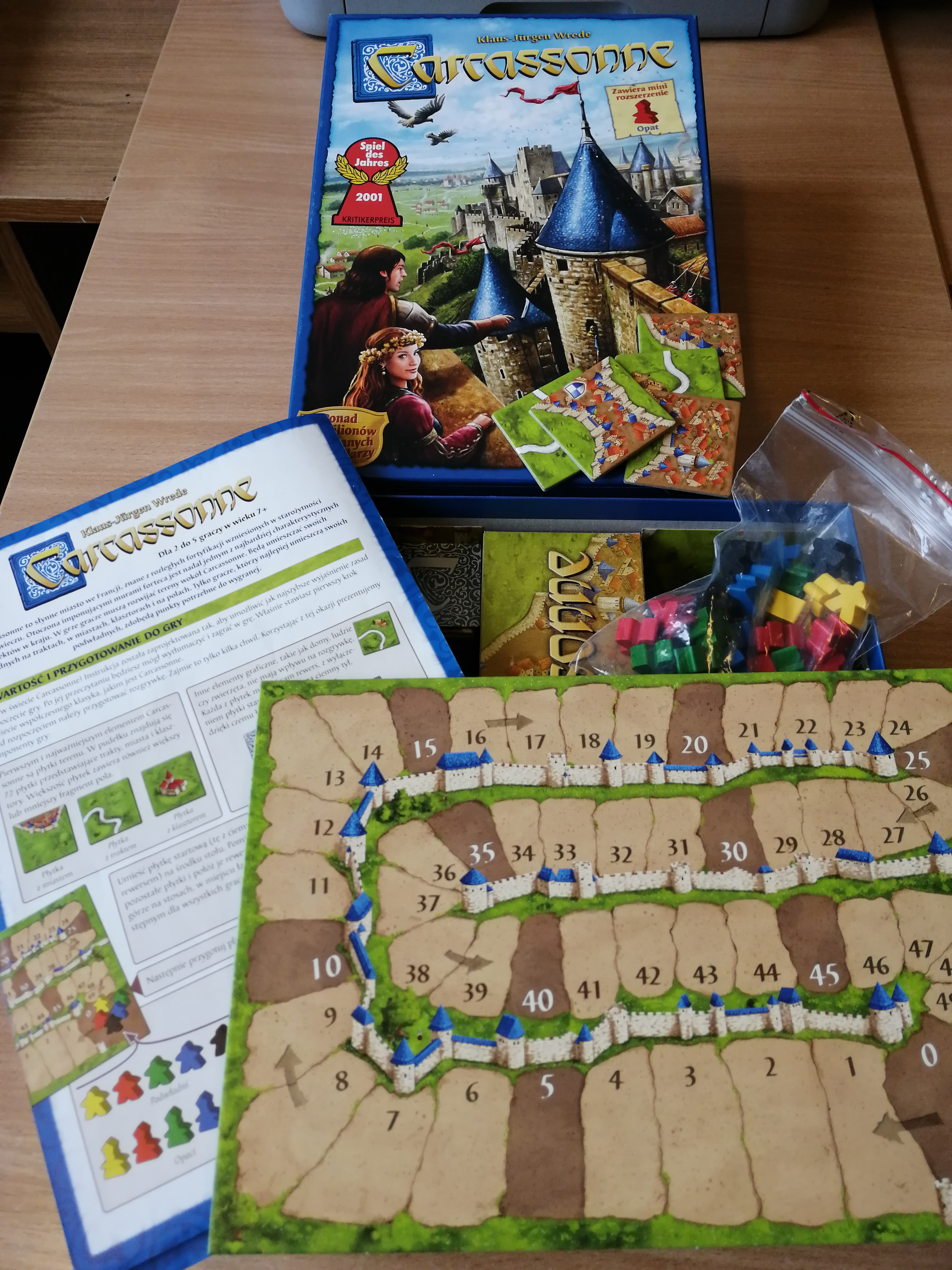 Rozpakowana gra gra planszowa Carcassonne. Widoczna plansza do gry i instrukcja do gry.