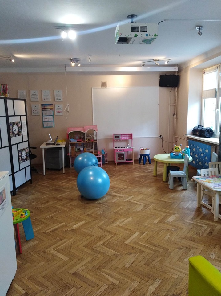 Zdjęcie sali z drabinkami na ścianie, piłką do ćwiczeń i miejscami do siedzenia (dla dorosłych i dzieci)